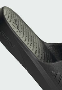 Black slide sandal with a textured sole, featuring a curved shape and "LIGHTSTRIKE" embossed detail on the side. Soft interior material.