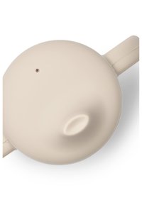 Rund beige tekanna med en slät matt yta, pip och handtag. Har ett litet hål nära toppen för ventilation.