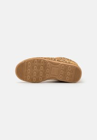 Chaussures à semelle en caoutchouc avec un dessus en imprimé léopard, présentant un design texturé et patterned dans des tons de jaune et de noir.