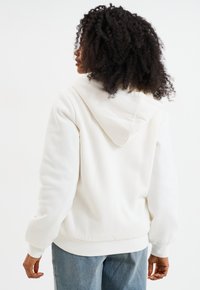 Witte hoodie met een losse pasvorm, verstelbare trekkoordkap, ribgebreide manchetten en zoom. Zacht materiaal met een gladde textuur.