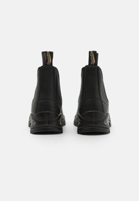 Schwarze Leder-Ankle-Boots mit elastischen Seitenpaneelen, runder Zehenpartie und strukturiertem Gummisohle. Goldfarbene Markierungs-Label auf der Rückseite.