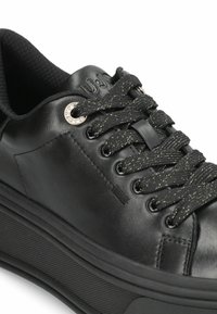 Baskets en cuir noir avec intérieur en tissu texturé, comportant des œillets métalliques pour les lacets, des lacets texturés avec des accents dorés, et une semelle rembourrée.