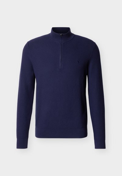Πουλόβερ με υφή πλεκτού σε ναυτικό μπλε χρώμα, με μακριά μανίκια, ψηλό γιακά και εμπρόσθιο κλείσιμο με φερμουάρ έως το ένα τέταρτο.