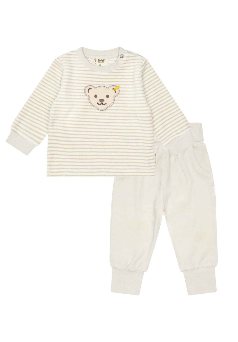 Maglietta a maniche lunghe a righe in crema chiara con applicazione di orsetto; abbinata a pantaloni morbidi color crema con polsini e vita elasticizzati.