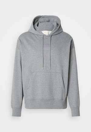 Grå hoodie i mjukt tyg, med en framficka, justerbar snörning i huvan och en fyrkantig patchdetalj på bröstet.