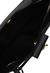 Zwarte leren tas met textuur en een ruime binnenkant, uitgerust met een gouden rits en hardware. De tas heeft een minimalistisch ontwerp en een open bovenkant.
