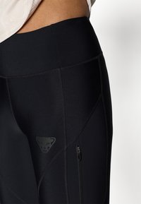 Mustad mustad leggings kõrge vöökoht, logode貼布, flatlock õmblused ja külgmine tõmblukk tasku hoiustamiseks.