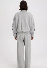 Grijze sweatshirt en bijpassende broek van zachte stof. De sweatshirt heeft een ontspannen pasvorm met verlaagde schouders en ribgebreide manchetten.