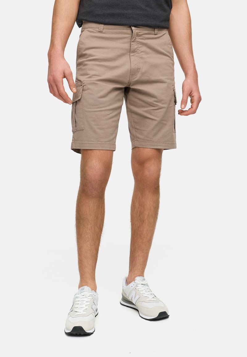Beige cargoshorts met een rechte snit, twee zijzakken en een zachte katoenmix. Gemonsterd met witte sportschoenen.