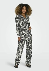 Zwart-wit bloemenpatroon loungwear-set met lange mouwen en wijde broekspijpen. Zacht materiaal, kraag en elastische tailleband.