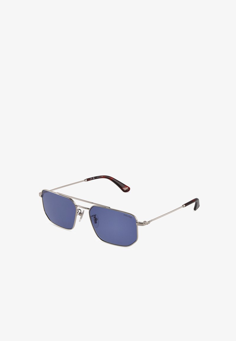 Lunettes de soleil à monture métallique argentée, verres rectangulaires bleus et branches fines avec embouts rouge foncé et noir.