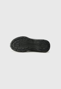 Zwarte atletische schoenenzool met geblokte rubber, voorzien van groeven en cirkelpatronen voor grip en flexibiliteit, ontworpen voor comfort en ondersteuning.