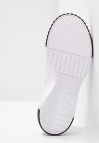Semelle blanche de chaussure de sport avec une surface texturée, un motif rainuré, et un accent noir contrastant sur le bord extérieur. Logo de la marque visible.