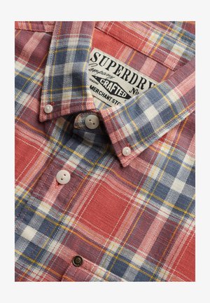 Close-up van de kraag en knopen van een roodblauw-wit geruit overhemd met zichtbare Superdry merklabel.