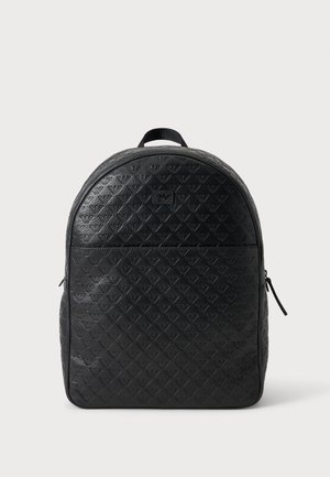 Sort læderrygsæk med præget diamantmønster og logoer, rundet top, front lynlåslomme og topbøjle mod en ensfarvet baggrund.