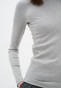 Grå ribbad långärmad topp med en figurnära design, som har en rund halsringning och något texturerad tyg, framtill prydd av en enkel fåll.