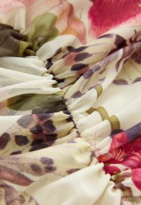 Bunt gemustertes Blumen-Mesh-Gewebe mit geraffter Textur. Besitzt weiche, durchscheinende Schichten in verschiedenen Farbtönen von Creme, Grün, Pink und Braun.