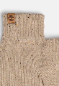 Beżowe, dziane rękawice bez palców z prążkowanym mankietem, z kolorowymi wtrąceniami oraz skórzaną metką z wytłoczonym logo drzewa.