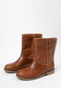 Leren enkellaarsjes in bruin met een gladde afwerking, een ronde neus en gestikte details aan de zijkant. Platte rubberen zool met minimale profiel; eenvoudig ontwerp.