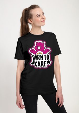 Sort kortærmet t-shirt med et pink bjørne grafik, en regnbue og teksten "BORN TO CARE" i fede bogstaver.
