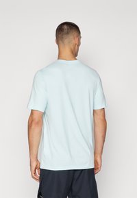Camiseta de algodón azul claro con manga corta, cuello redondo y un corte relajado. Textura suave, sin patrones ni acentos visibles.