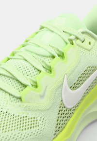 Zapatilla atlética verde lima con parte superior de malla, cordones texturizados y un logo de swoosh blanco. La suela tiene un acento vibrante y un diseño aerodinámico.