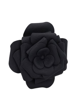 Schwarze Lederblume mit mehreren strukturierten Blütenblättern, die in Rosenform auf weißem Hintergrund geschichtet sind.