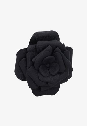 Schwarze Lederblume mit mehreren strukturierten Blütenblättern, die in Rosenform auf weißem Hintergrund geschichtet sind.