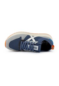 Scarpa sportiva blu in rete e grigia in suede con accenti bianchi, suola in gomma testurizzata, lacci piatti e un inserto sul tallone colorato. Etichetta della taglia visibile all'interno.