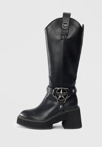 Melnas ādas kovboju zābaki ar vidukļa augstumu, masīlu papēdi, sudraba zvaigžņu akcentiem un jostu sprādzi ar zvaigznes dizainu.