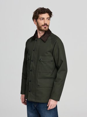 Giacca verde oliva con chiusura a bottoni, colletto in velluto a coste marrone e quattro tasche frontali. Tessuto liscio con design strutturato.