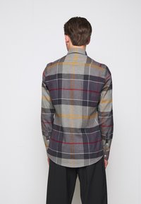 Grau kariertes Hemd mit Knopfleiste, das rote, gelbe und marineblaue Linien aufweist. Es hat lange Ärmel und einen abgerundeten Saum und ist aus einem strukturierten Stoff gefertigt.