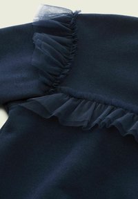 Felpa blu navy con una texture morbida, caratterizzata da un accento di tulle arricciato lungo la cucitura della spalla.
