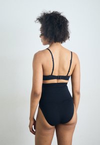 Svart høy midje bikini med justerbare stropper. Slitesterk tekstur, minimalistisk design, med lås bak.