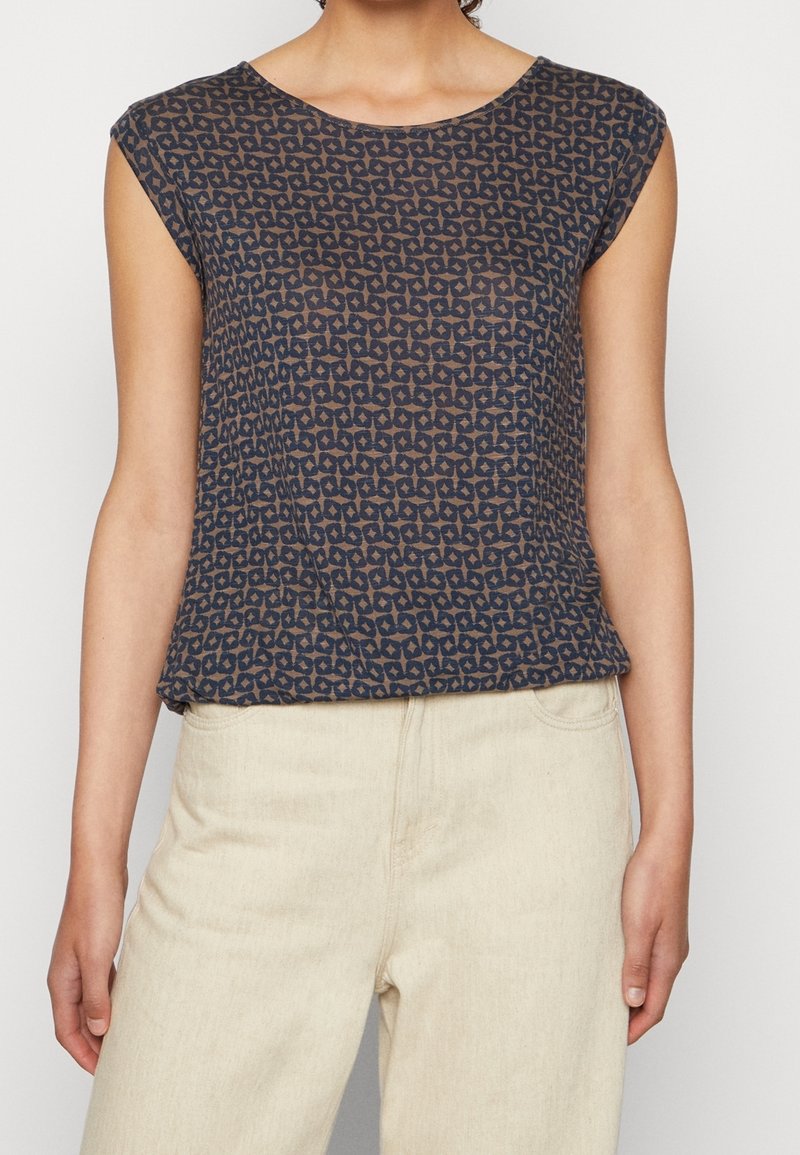 Blouse à motifs marins avec un col rond et des manches courtes, présentant un design géométrique aux teintes plus claires. Tissu léger et semi-transparent.