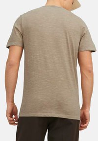 Lichtbruine t-shirt met korte mouwen, gemaakt van een zachte, gestructureerde stof. Crew neck ontwerp, lichtjes losse pasvorm en een rechte zoom bij de taille.