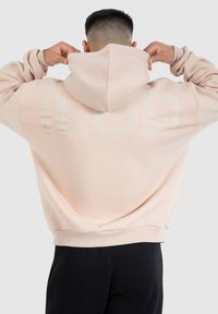 Sweatshirt à capuche rose clair avec un grand imprimé tonal "LOD" au dos, présentant des poignets et un ourlet côtelés, avec une coupe décontractée.