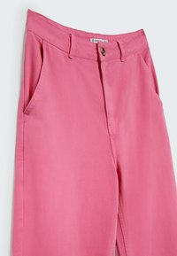Pantalon en coton rose taille haute avec poches latérales, passants de ceinture et fermeture par bouton à la taille.