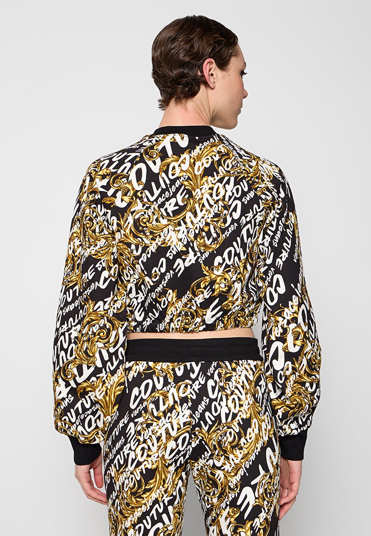 Sweatshirt mit schwarzem und goldenem Muster und cropped Design, mit Text und eleganten Elementen. Enganliegende Bündchen und Saum in einfarbig Schwarz.
