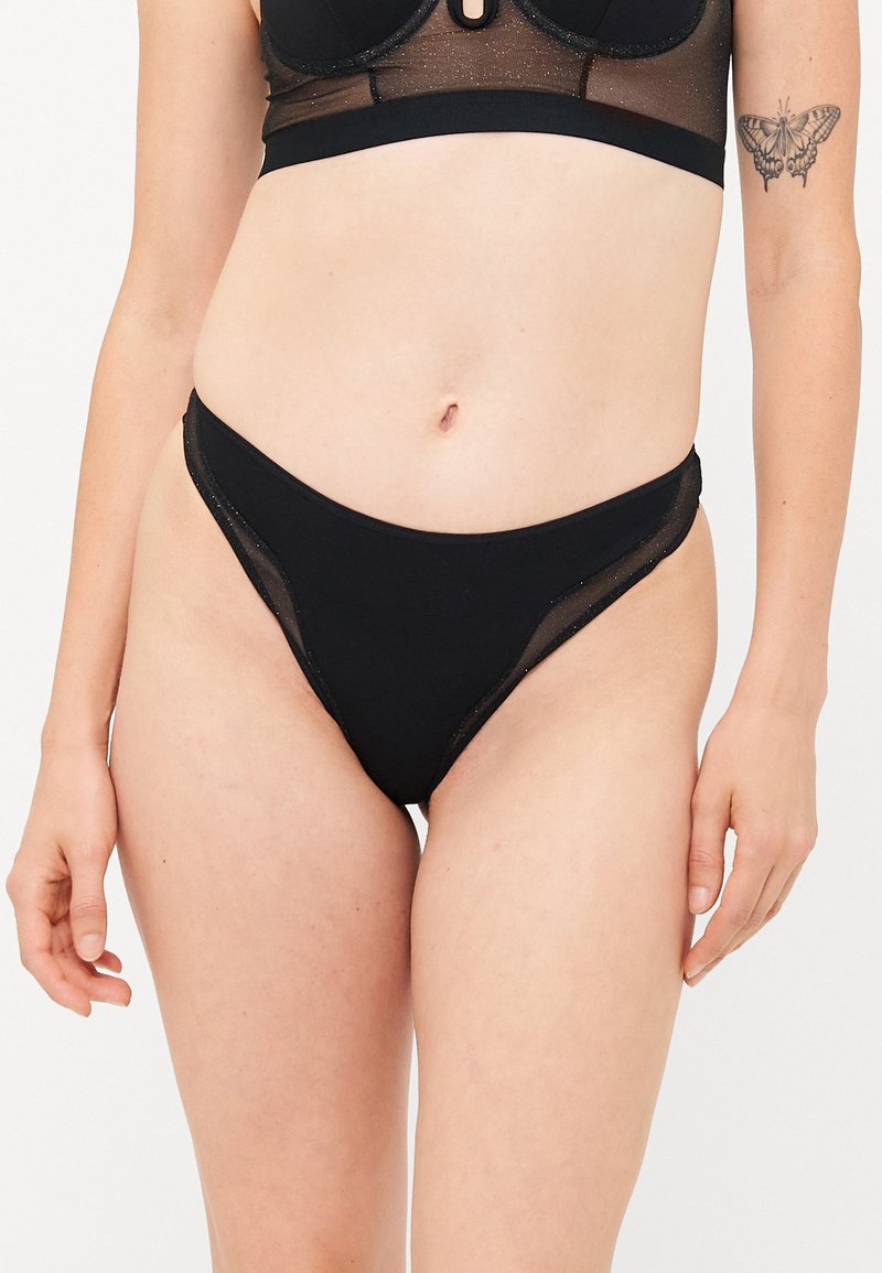 Black bikini bottoms featuring a minimalist design, made of smooth fabric with mesh accents on the sides and a low-rise fit.