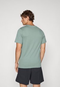 Camiseta verde de manga corta con cuello redondo y una textura suave. La tela es ligera y la prenda tiene un corte holgado.