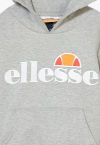 Grijze hoodie met een groot wit "ellesse" logo op de voorkant en een oranje en rode halfronde vorm erboven. Zachte stof en voorzak.