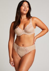 Hautfarbene Unterwäsche in einem Set, bestehend aus einem Spitzen-BH mit floraler Stickerei und passenden hochgeschnittenen Panties, beide mit gewellten Kanten.