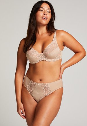 Set di lingerie color nude composto da un reggiseno in pizzo con ricami floreali e coordinati slip a vita alta, entrambi con bordi svolazzanti.