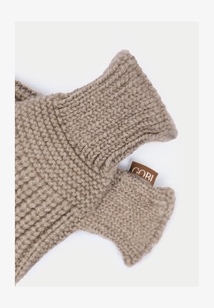 Große beige gestrickte fingerlose Handschuhe mit gerippten Bündchen und einem sichtbaren braunen Stoffetikett auf weißem Hintergrund.