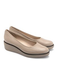 Beżowe skórzane buty na koturnie z okrągłymi czubkami, delikatną fakturą i kontrastującym czarnym wykończeniem wzdłuż podeszwy. Lekka konstrukcja zapewniająca komfort.