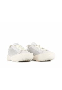 Sneakers grigio chiaro con lati in mesh, punta rotonda e suola bianca texturizzata. Presentano una chiusura in pizzo morbida e un design minimalista.