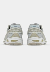 Sport shoes featuring a light gray mesh upper with beige accents, padded collar, and white sole with gel cushioning detail at the heel.