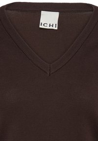Pull en maille côtelée brun foncé avec col en V et une étiquette blanche de la marque ICHI cousue à l'intérieur de l'encolure.
