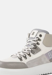 Wysokie trampki z panelami w kolorach białym, szarym i jasnofioletowym, metalowymi oczkami, białymi sznurowadłami oraz teksturowaną podeszwą na białym tle.